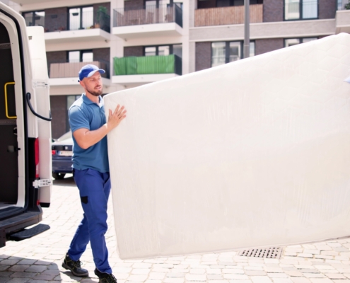 Zwei Logistikmitarbeiter liefern eine große Matratze aus – professioneller Versand für Private Label und Dropshipping im Matratzenhandel